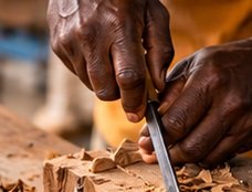 Hands carving a traditional wooden object
